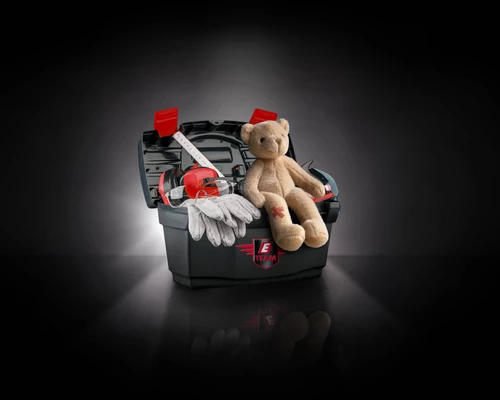 Werkzeugkiste mit Handschuhen, Schutzbrille und Teddybär mit Pflaster.
